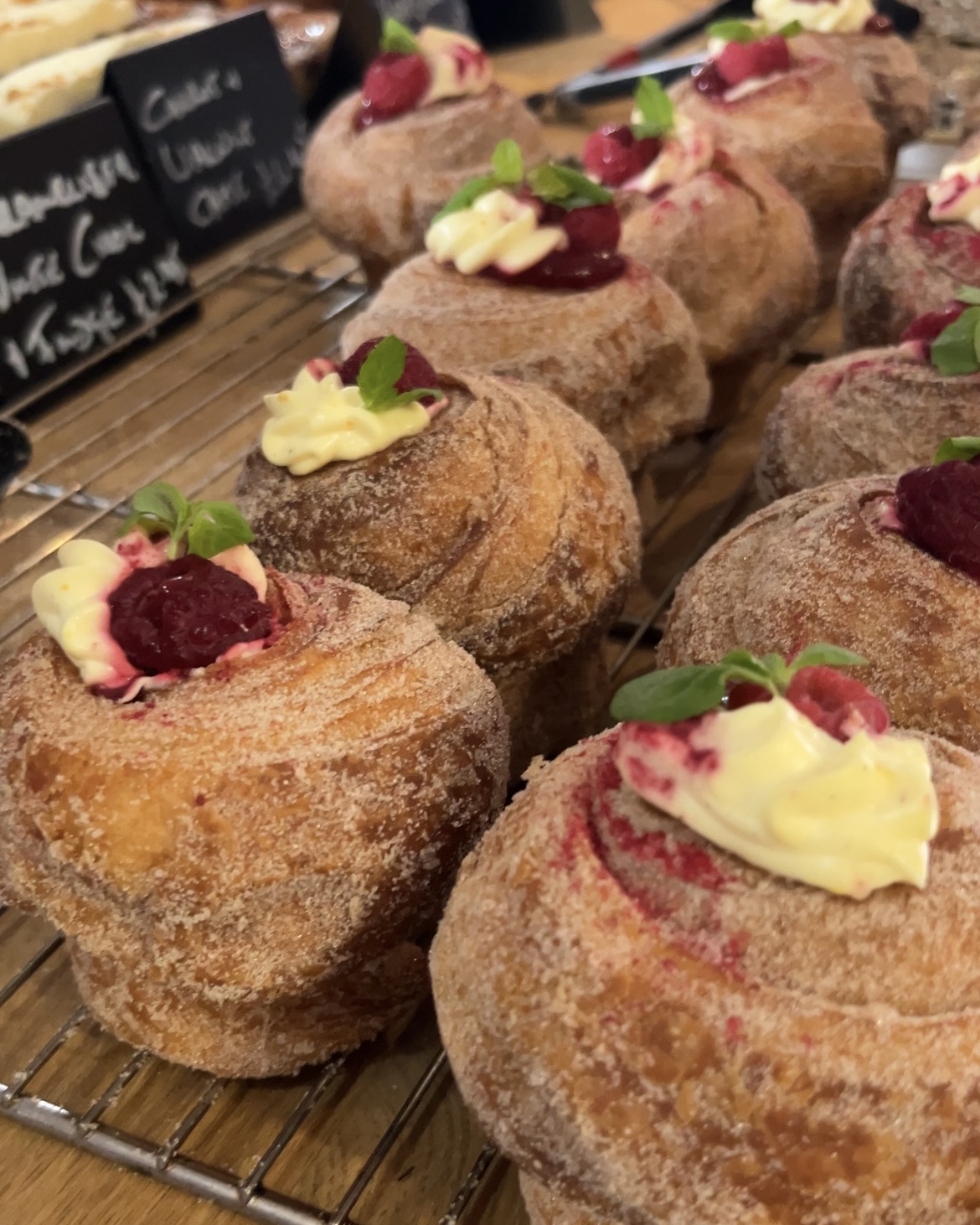 Freshly baked raspberry cheesecake cruffins topped with powdered sugar and fresh raspberries